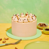 Classic Coffee & Walnut Cake by Crumbs & Doilies with Swiss Meringue icing and walnut decoration on green plate.